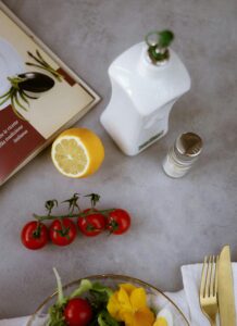 Flat lay of fresh vegetables, lemon, and olive oil for composing a healthy salad.